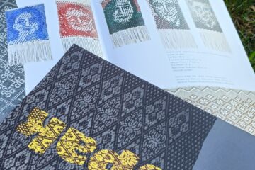 Otwarty katalog wystawy sejpak na nim leży drugi zamknięty z napisem sejpak