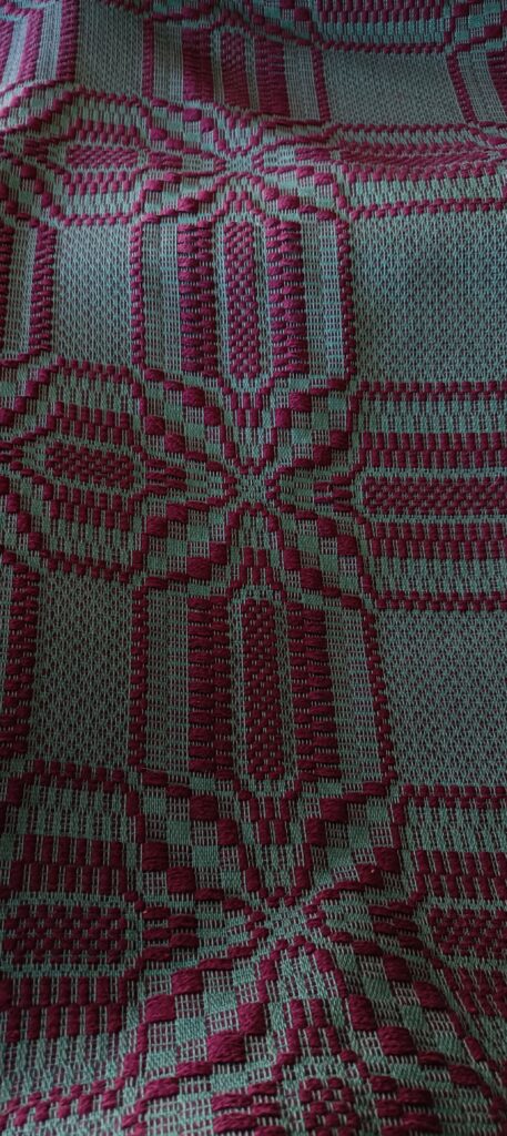 Tkanina na krośnie poziomym, na zielonej osnowie wzór wątku bordo, tkanina radziuszka tzw. motyle