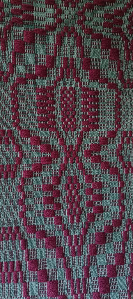 Tkanina na krośnie poziomym, na zielonej osnowie wzór wątku bordo, tkanina radziuszka tzw. motyle