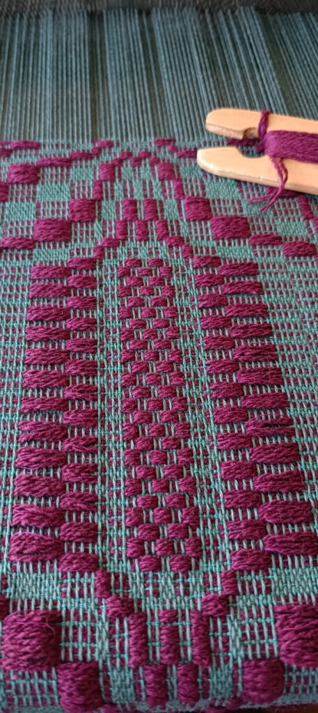 Tkanina na krośnie poziomym, na zielonej osnowie wzór wątku bordo, tkanina radziuszka tzw. motyle